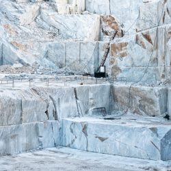 Open cast mine pit with white Carrara marble being cut into rectangular blocks for the construction industry and sculptures in Tuscany, Italy